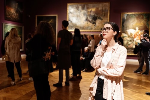 Frau beobachtet nachdenklich während eines Museumstages ein Ausstellungsobjekt